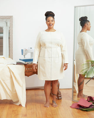 Woman in a white dress standing in a room with mirrors and sewing equipment. This dress is the Wyman Dress Sloper sewing pattern from Cashmerette.