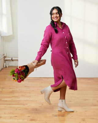 Woman in a pink dress holding flowers in a room with wooden floor and white walls. This dress is the Winvale Dress & Tunic sewing pattern from Cashmerette.