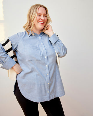 Woman wearing a light blue button-up shirt with black and white striped sleeves against a plain background. This dress is the Winvale Dress & Tunic sewing pattern from Cashmerette.