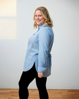Woman wearing a light blue jacket against a white wall. This dress is the Winvale Dress & Tunic sewing pattern from Cashmerette.
