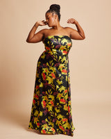 Woman wearing a strapless floral dress on a beige background. This dress is the Ellington Strapless Dress sewing pattern from Cashmerette.