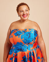 Woman wearing a strapless dress with blue floral pattern on a beige background. This dress is the Ellington Strapless Dress sewing pattern from Cashmerette.