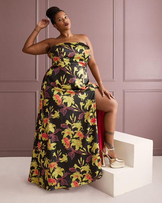 Woman wearing a floral strapless dress against a pink paneled wall. This dress is the Ellington Strapless Dress sewing pattern from Cashmerette.