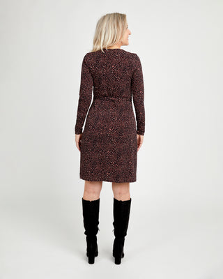 Woman wearing a patterned dress with long sleeves and a belt, standing against a white background.This dress is the Appleton Wrap Dress sewing pattern from Cashmerette.