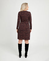 Woman wearing a patterned dress with long sleeves and a belt, standing against a white background.This dress is the Appleton Wrap Dress sewing pattern from Cashmerette.