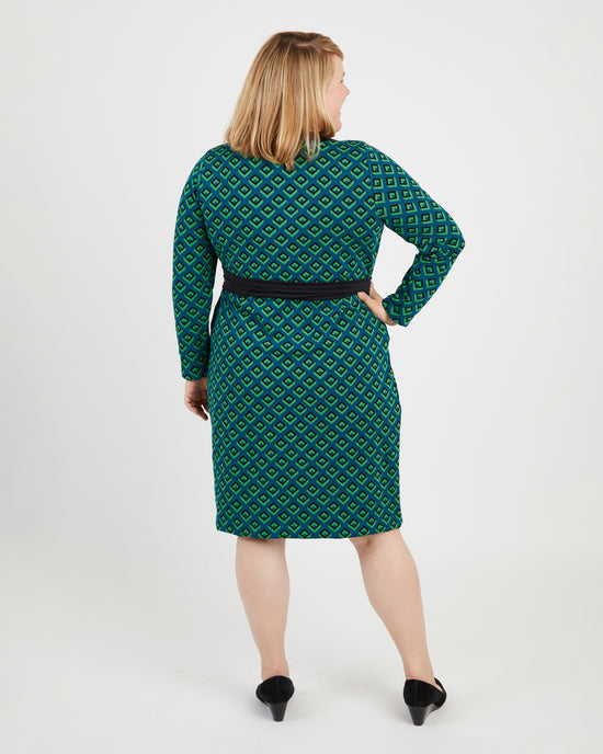 Woman wearing a green patterned dress on a white background. This dress is the Appleton Wrap Dress sewing pattern from Cashmerette.