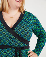 Woman wearing a green and black patterned dress with a black belt. This dress is the Appleton Wrap Dress sewing pattern from Cashmerette.