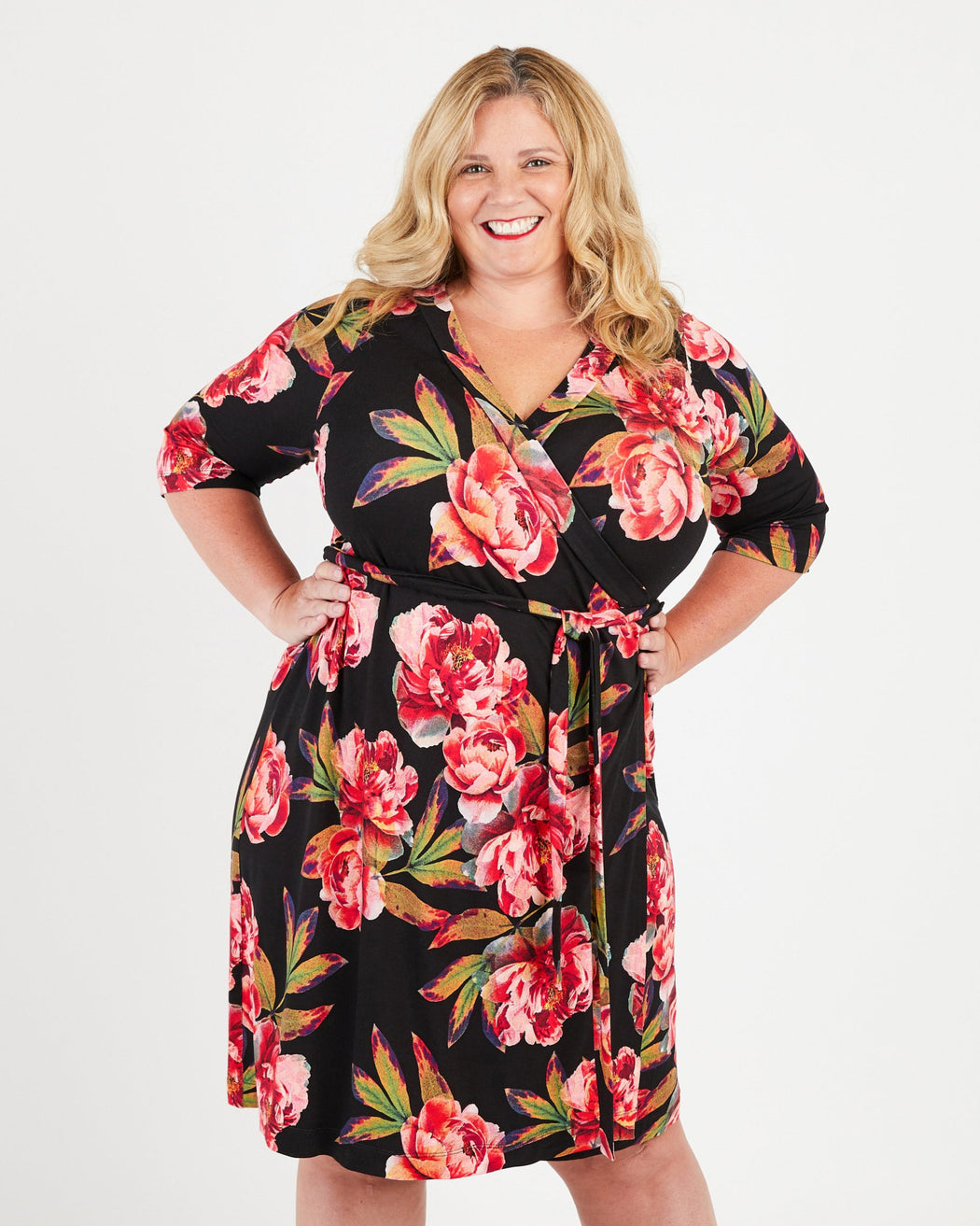 Woman wearing a floral dress on a white background. This dress is the Appleton Wrap Dress sewing pattern from Cashmerette.