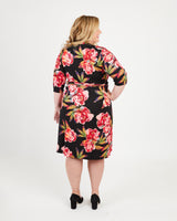 Woman wearing a black floral dress on a white background. This dress is the Appleton Wrap Dress sewing pattern from Cashmerette.