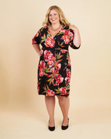 Woman wearing a floral dress on a beige background. This dress is the Appleton Wrap Dress sewing pattern from Cashmerette.