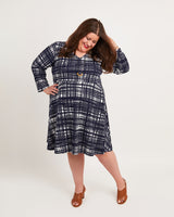Woman wearing a blue plaid dress on a white background. This dress is the Turner Dress sewing pattern from Cashmerette.