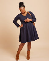 Woman wearing a navy blue dress with long sleeves on a beige background