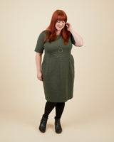 Woman wearing a green dress with a beige background. This dress is the Rivermont Dress & Top sewing pattern from Cashmerette.