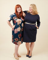 Two women wearing navy dresses with floral and plain designs on a beige background. This dress is the Rivermont Dress & Top sewing pattern from Cashmerette.