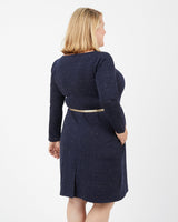 Woman wearing a navy blue dress with a matching cardigan on a white background. This dress is the Rivermont Dress & Top sewing pattern from Cashmerette.