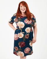 Woman wearing a floral dress on a white background. This dress is the Rivermont Dress & Top sewing pattern from Cashmerette.