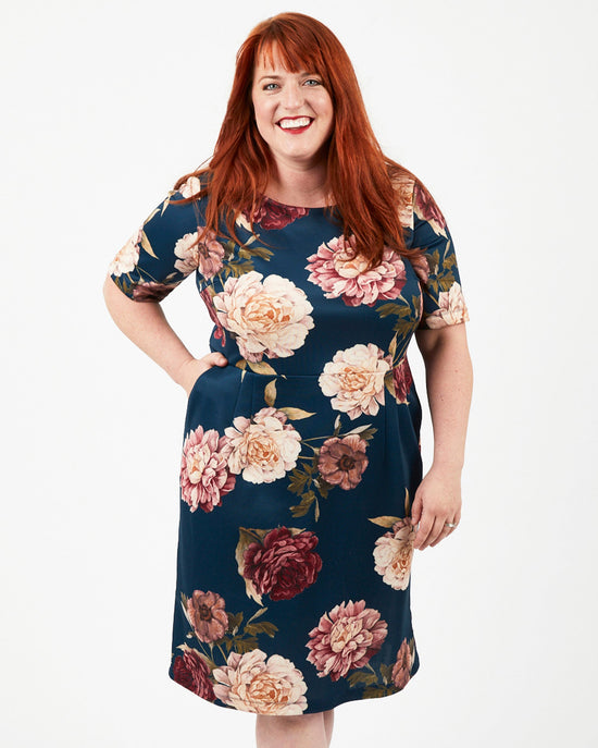 Woman wearing a floral dress on a white background. This dress is the Rivermont Dress & Top sewing pattern from Cashmerette.