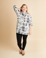 Woman wearing a patterned blouse and black leggings on a beige background. This is the Pembroke Dress & Tunic sewing pattern from Cashmerette.