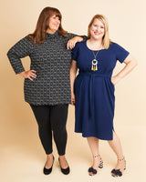 Two women standing side by side wearing black and blue dresses against a beige background. This is the Pembroke Dress & Tunic sewing pattern from Cashmerette.