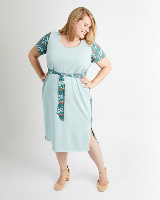 Woman wearing a light blue dress with floral sleeves on a white background. This is the Pembroke Dress & Tunic sewing pattern from Cashmerette.