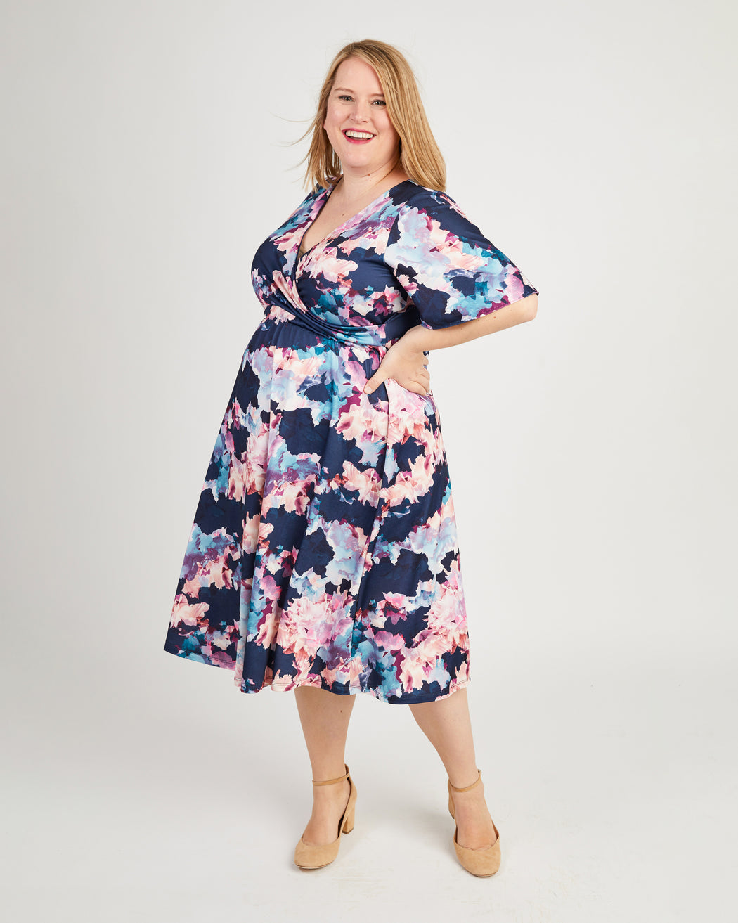 Woman wearing a floral dress on a white background. This dress is the Alcott Dress sewing pattern from Cashmerette.