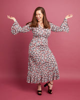 Woman wearing a floral dress against a pink background. This dress is the Alcott Dress sewing pattern from Cashmerette.