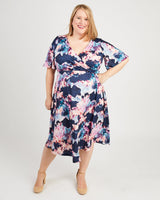 Woman wearing a floral dress on a white background. This dress is the Alcott Dress sewing pattern from Cashmerette.