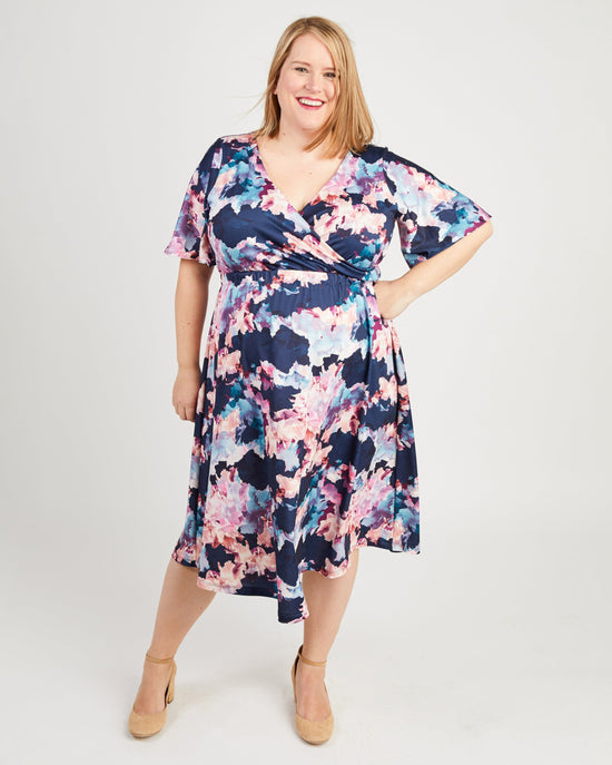 Woman wearing a floral dress on a white background. This dress is the Alcott Dress sewing pattern from Cashmerette.