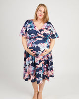 Woman wearing a floral dress on a white background. This dress is the Alcott Dress sewing pattern from Cashmerette.
