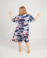 Woman wearing a floral dress with a white background. This dress is the Alcott Dress sewing pattern from Cashmerette.
