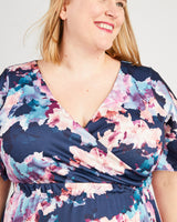 Woman wearing a floral dress with a white background. This dress is the Alcott Dress sewing pattern from Cashmerette.