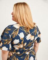 Woman wearing a floral dress with a white background. This dress is the Alcott Dress sewing pattern from Cashmerette.
