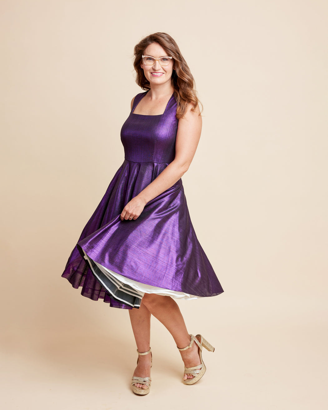 Woman wearing a purple dress on a beige background. This is the Grafton Dress, Top & Skirt sewing pattern from Cashmrette.