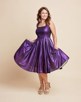 Woman wearing a purple dress on a beige background. This is the Grafton Dress, Top & Skirt sewing pattern from Cashmrette.