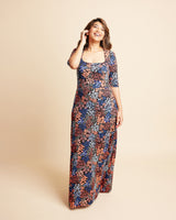 Woman wearing a floral dress on a beige background. This is the Grafton Dress, Top & Skirt sewing pattern from Cashmrette.