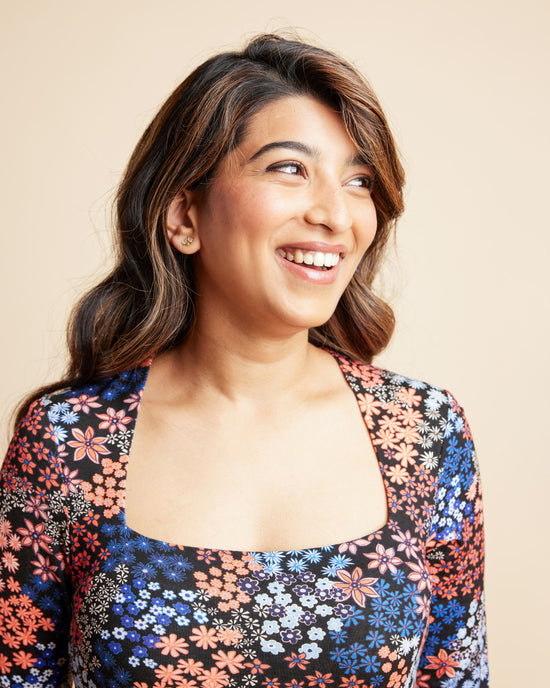 Woman wearing a floral top against a beige background. This is the Grafton Dress, Top & Skirt sewing pattern from Cashmrette.