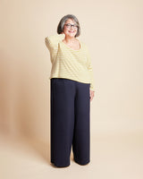 Woman wearing a yellow striped shirt and navy pants against a beige background. This is the Grafton Dress, Top & Skirt sewing pattern from Cashmerette.