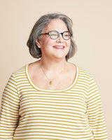 Woman wearing a yellow and white striped shirt against a beige background. This is the Grafton Dress, Top & Skirt sewing pattern from Cashmerette.