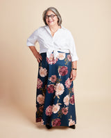 Woman wearing a white blouse and floral skirt on a beige background. This is the Grafton Dress, Top & Skirt sewing pattern from Cashmerette.