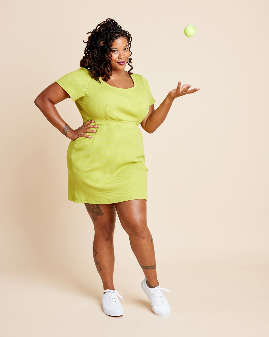 Woman wearing a bright green dress against a beige background. This is the Grafton Dress, Top & Skirt sewing pattern from Cashmerette.