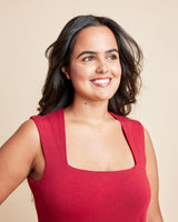 Woman wearing a red sleeveless top against a beige background. This is the Grafton Dress, Top & Skirt sewing pattern from Cashmrette.