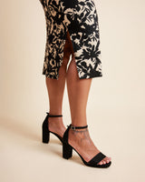 Person wearing a floral skirt and black high-heeled shoes on a beige background. This is the Grafton Dress, Top & Skirt sewing pattern from Cashmrette.
