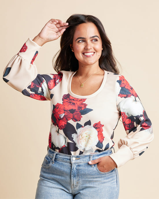 Woman wearing a floral blouse with a beige background. This is the Grafton Dress, Top & Skirt sewing pattern from Cashmrette.