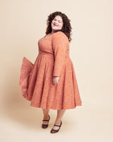 Woman wearing a red floral dress against a beige background. This is the Grafton Dress, Top & Skirt sewing pattern from Cashmerette.