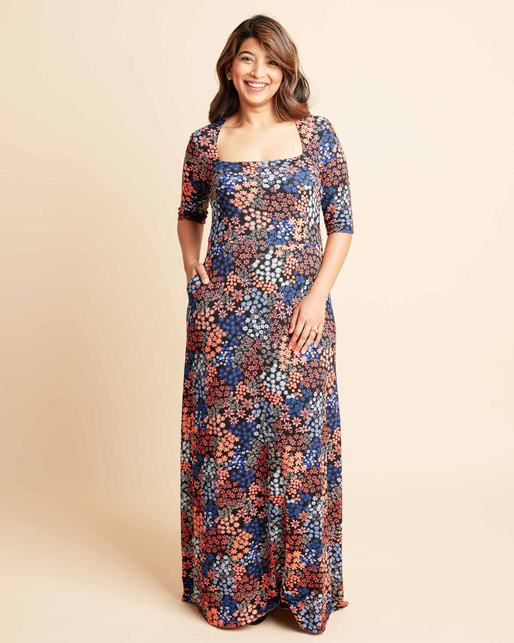 Woman wearing a floral dress on a beige background. This is the Grafton Dress, Top & Skirt sewing pattern from Cashmrette.