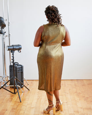 Person wearing a gold dress standing in a studio setting with photography equipment. This dress is the Dewey Dress sewing pattern from Cashmerette.