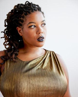 Woman wearing a gold sleeveless top against a white background. This dress is the Dewey Dress sewing pattern from Cashmerette.