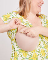 Woman wearing a floral dress with a beige bralette underneath on a plain background. This is the nursing expansion pack sewing pattern from Cashmerette.