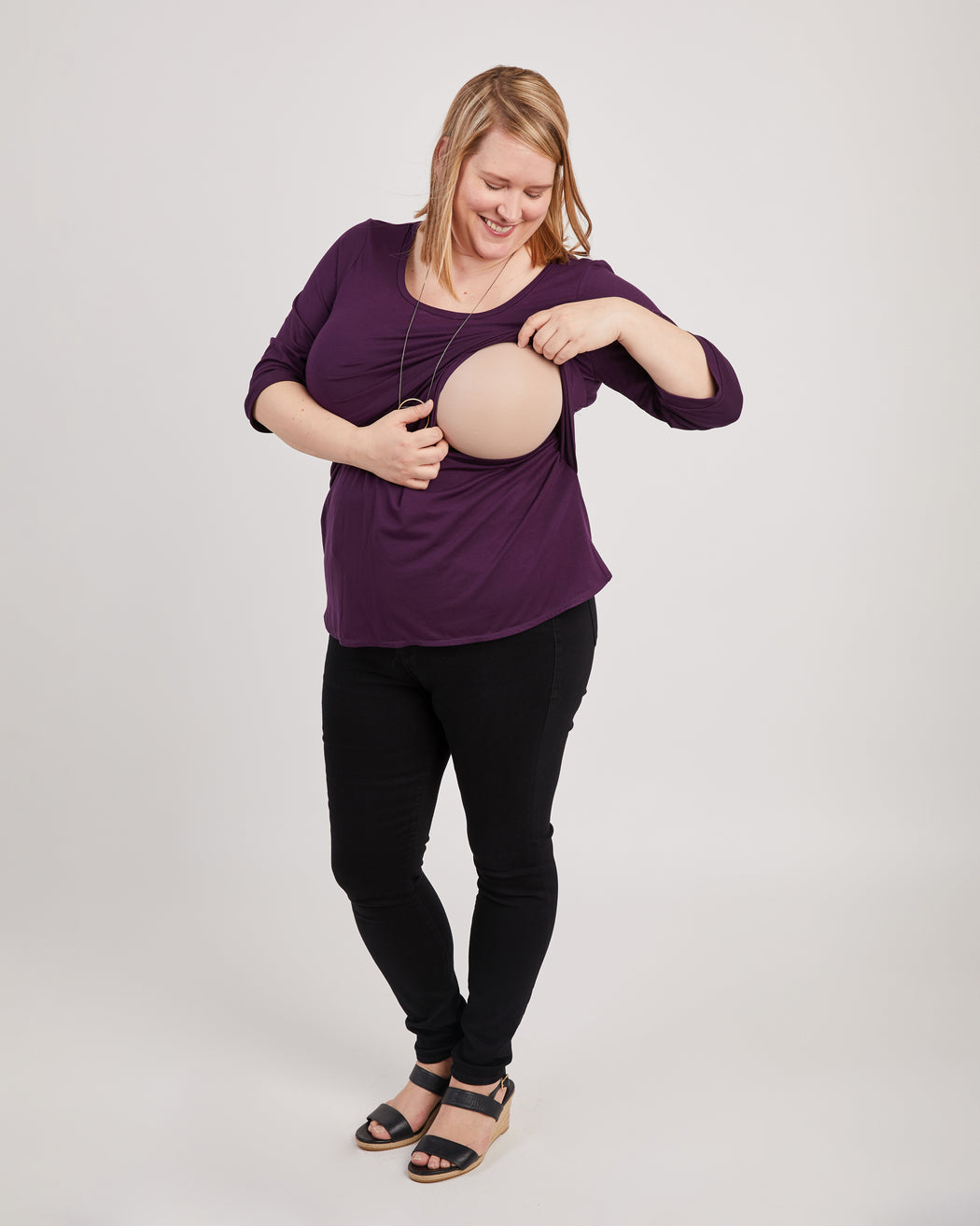 Woman wearing a loose-fitting purple shirt and black pants on a plain background. This is the nursing expansion pack sewing pattern from Cashmerette.