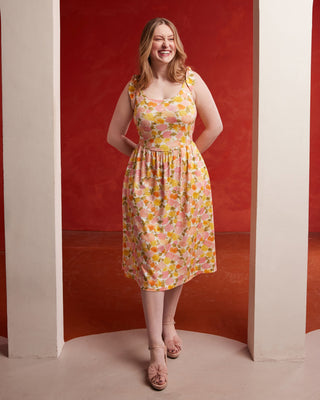 Woman in a floral dress standing in a red and beige archway. This dress is the Irving Dress sewing pattern from Cashmerette.